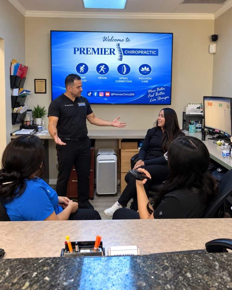 Dr. Jesús Cazares talks with three members of the Premier Chiropractic front desk team at the reception area in Stockton