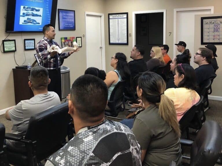 Dr. Jesús Cazares holds a spine model while he teaches a class for patients at Premier Chiropractic
