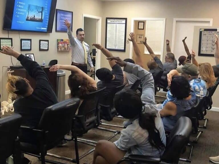 Patients raise their arms to stretch during a class led by Dr. Jesús Cazares at Premier Chiropractic